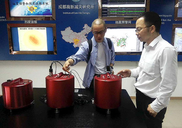 Wang Tun (right), head of the Chengdu-based Institute of Care-Life, demonstrates a seismic monitoring station. (Photo: China Daily/Huang Zhiling)