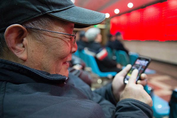 An investor browses stock information with his smartphone at a brokerage in Nanjing, Jiangsu province. (Photo provided to China Daily) An investor browses stock information with his smartphone at a brokerage in Nanjing, Jiangsu province. (Photo provided to China Daily)