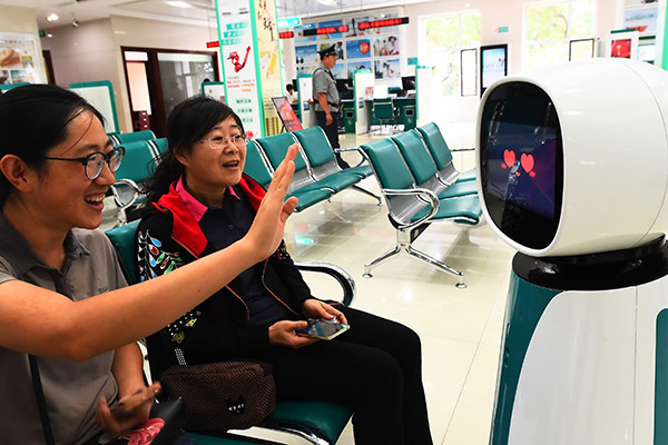 Two women interact with a robot, which helps handle business, at an outlet of Agricultural Bank of China in Qingzhou, Shandong province. (Photo/China Daily) Two women interact with a robot, which helps handle business, at an outlet of Agricultural Bank of China in Qingzhou, Shandong province. (Photo/China Daily)