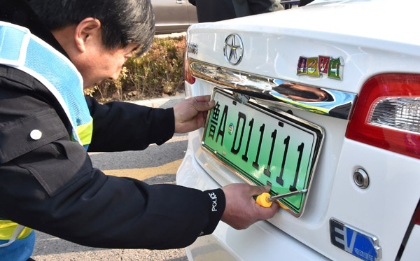 An employee of the Jinan vehicle administration department installs a plate on an electric car in Jinan, Shandong province, Dec 1, 2016. (Photo for China Daily) An employee of the Jinan vehicle administration department installs a plate on an electric car in Jinan, Shandong province, Dec 1, 2016. (Photo for China Daily)