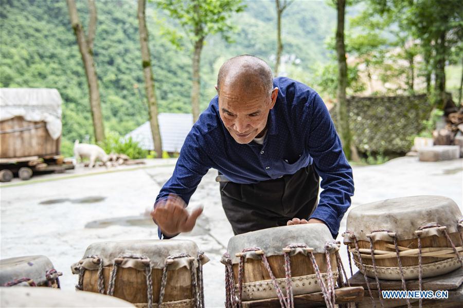 Wu Kaixue checks the sound of Dingtang drums at his courtyard in Longtan Village, Shennongjia of central China\'s Hubei Province, May 21, 2018. Wu Kaixue, who is 75 years old, began to learn the making of Dingtang drums when he was 13. The making of Dingtang drums needs natural resources from the Shennongjia forest and also requires high standard of techniques. Wu makes 100 plus drums in a year and his fame has spread far away. (Xinhua/Du Huaju)