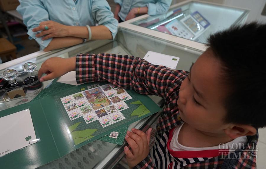 A boy, accompanied by his mother, stamps his souvenir travelling frog stamp folder. (Photo: Xiang Jun/GT)