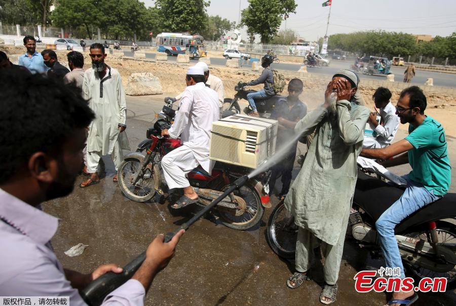 Pakistani volunteer spray water on people to keep them cool in Karachi, Pakistan, May 21, 2018. The Meteorological Department has issued a heat-wave alert for three days. (Photo/Agencies)