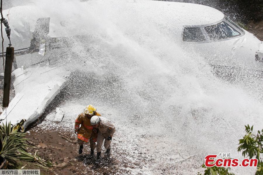 Firefighters take cover from firefighting foam applied onto the wreckage of a Gulfstream G200 aircraft that skidded off the runway during landing at Toncontin International Airport in Tegucigalpa, Honduras, May 22, 2018. At least six passengers were injured. (Photo/Agencies)