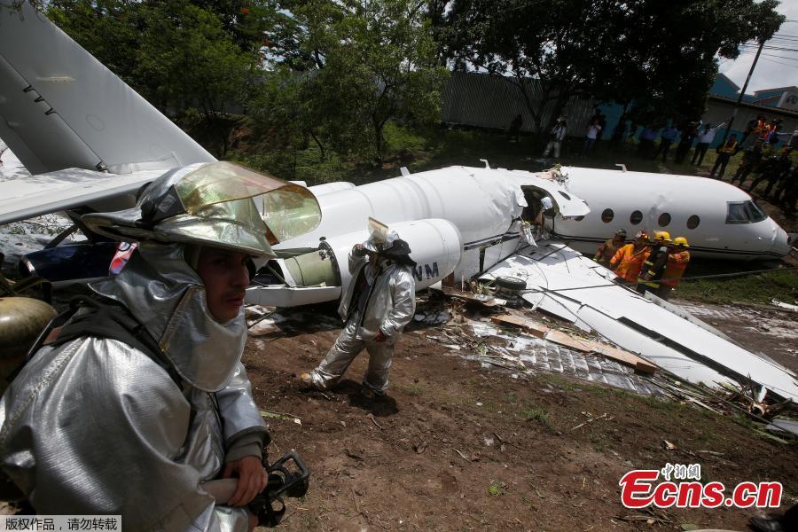 Firefighters stand near a Gulfstream G200 aircraft that skidded off the runway during landing at Toncontin International Airport in Tegucigalpa, Honduras, May 22, 2018. At least six passengers were injured. (Photo/Agencies)