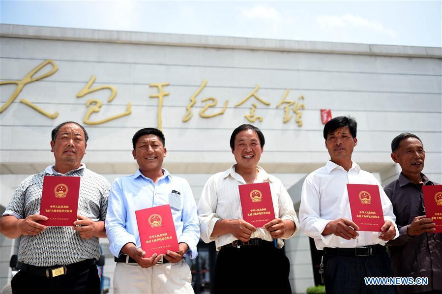 Farmers show rural land contract of management warrants at Xiaogang Village in Fengyang County, east China\'s Anhui Province, July 8, 2015. This year marks the 40th anniversary of China\'s starting to implement reform and opening up policy. (Xinhua/Liu Junxi)