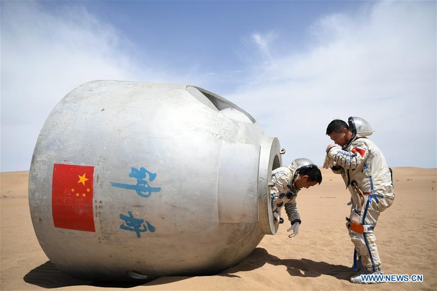 Taikonauts Nie Haisheng (L) and Liu Wang exit from a re-entry capsule during a wilderness survival training in the Badain Jaran Desert in northwest China\'s Gansu Province, May 17, 2018. Fifteen Chinese taikonauts have just completed desert survival training deep in the Badain Jaran Desert near Jiuquan Satellite Launch Center in northwest China. Organized by the Astronaut Center of China (ACC), the program was designed to prepare taikonauts with the capacity to survive in the wilderness in the event their re-entry capsule lands off target. (Xinhua/Chen Bin)