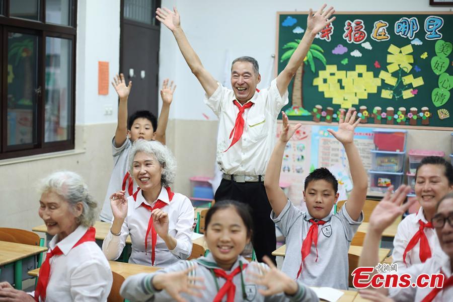 Photo taken on May 28, 2018 shows five elderly people, 73 years old on average, put on white shirts and red scarfs to pose for an awareness event in the run up to Children’s Day at an elementary school in Nanjing, East China’s Jiangsu Province. Organizer said the event aimed to inspire more people to take care of elderly people. (Photo: China News Service/Yang Bo)