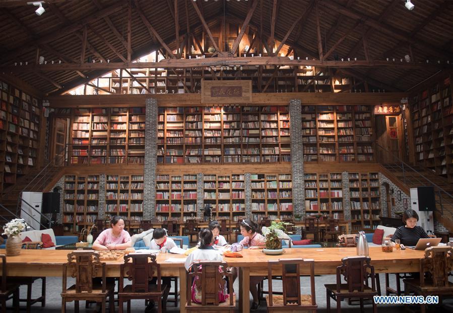 Students of Miaoqian Village study at the library in a hostel in Moganshan Town in Deqing County, east China\'s Zhejiang Province, May 29, 2018. The owner of the hostel Zhu Jindong, who worked in publishing, founded the hostel in 2015. The library collecting about 20,000 books in the hostel made it famous and attracted many tourists. (Xinhua/Weng Xinyang)