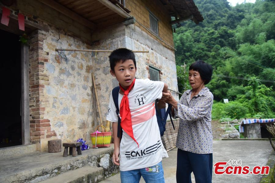 Li Jianwen, 10, is helped by his great-grandmother before going to Dayadong Primary School in Liucheng County, South China’s Guangxi Zhuang Autonomous Region, May 31, 2018. (Photo: China News Service/Wang Yizhao)