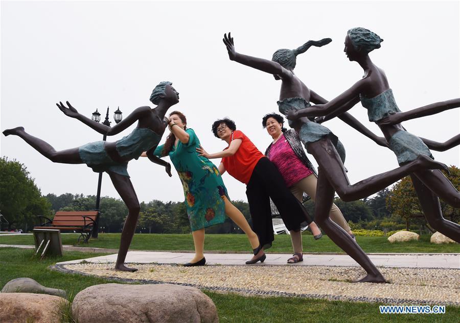 Citizens pose for photo at the Olympic Park in Qingdao, east China\'s Shandong Province, June 4, 2018. The 18th Shanghai Cooperation Organization (SCO) Summit is scheduled for June 9 to 10 in Qingdao. (Xinhua/Li Ziheng)
