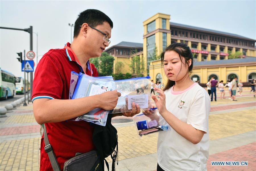 A teacher distributes ID cards and stationery to examinees at an exam venue in Chengdu, capital of southwest China\'s Sichuan Province, June 7, 2018. About 9.75 million students have registered for the national college entrance examination, which takes place from June 7 to 8. (Xinhua/Jiang Hongjing)
