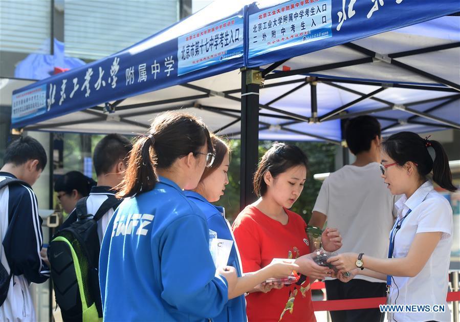 A staff member checks the credentials of examinees at an exam venue in Beijing, capital of China, June 7, 2018. About 9.75 million students have registered for the national college entrance examination, which takes place from June 7 to 8. (Xinhua/Luo Xiaoguang)