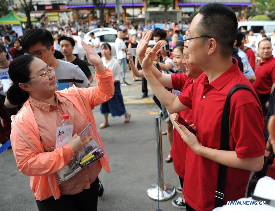 An examinee claps hands with her teacher before entering an exam venue in Xi\'an, capital of northwest China\'s Shaanxi Province, June 7, 2018. About 9.75 million students have registered for the national college entrance examination, which takes place from June 7 to 8. (Xinhua/Zhang Bowen)