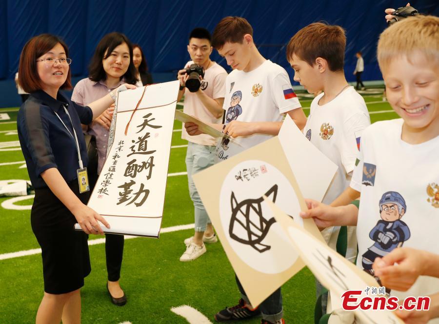 Zhang Ye, principal of Beijing Huijia Private School, presents gifts to visiting Russian teenager ice hockey players in Beijing, June 11, 2018. (Photo: China News Service/Liu Guanguan)