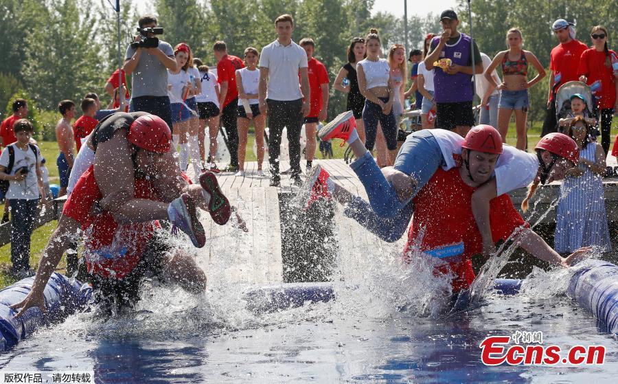 Men carry their wives over a water obstacle while racing in the Wife Carrying competition to mark the City Day in Krasnoyarsk, Russia, June 10, 2018. (Photo/Agencies)