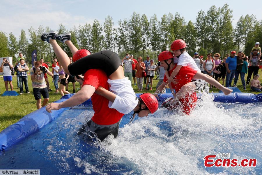 Men carry their wives over a water obstacle while racing in the Wife Carrying competition to mark the City Day in Krasnoyarsk, Russia, June 10, 2018. (Photo/Agencies)