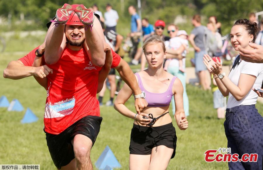 A man carries his wife while racing in the Wife Carrying competition to mark the City Day in Krasnoyarsk, Russia, June 10, 2018. (Photo/Agencies)