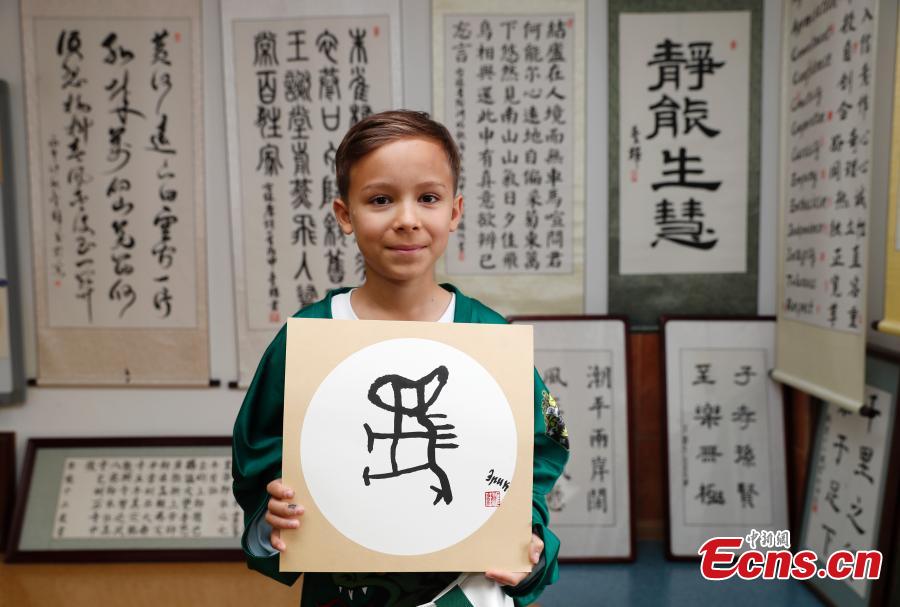 A Russian teenager ice hockey player shows a Chinese calligraphy work during a visit to Beijing Huijia Private School in Beijing, June 11, 2018. (Photo: China News Service/Liu Guanguan)