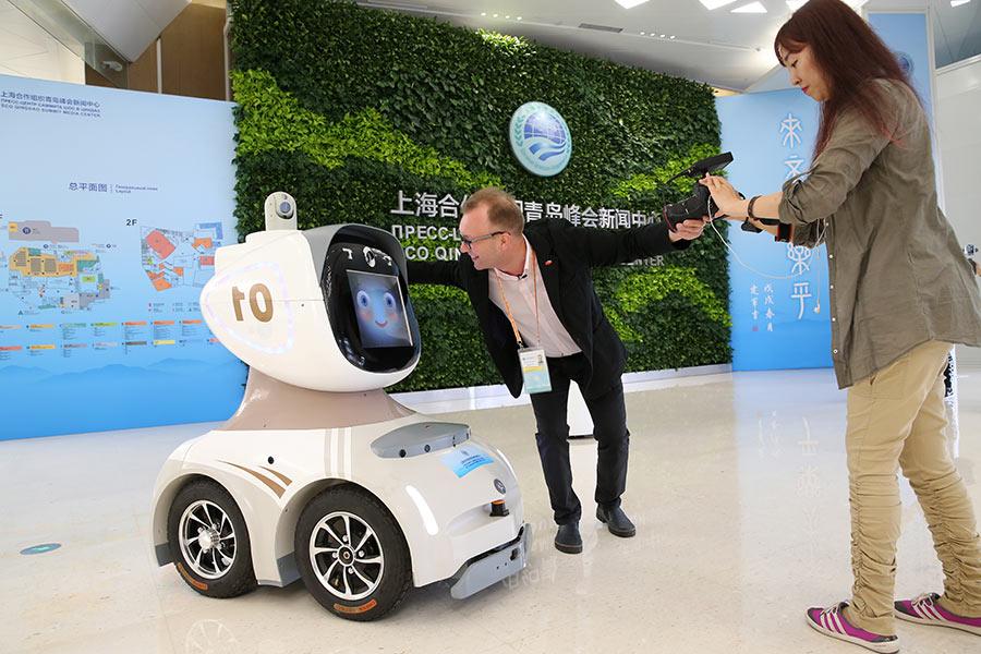 Journalists photograph a security robot at the news center of the summit on Friday. (Photo/China Daily)