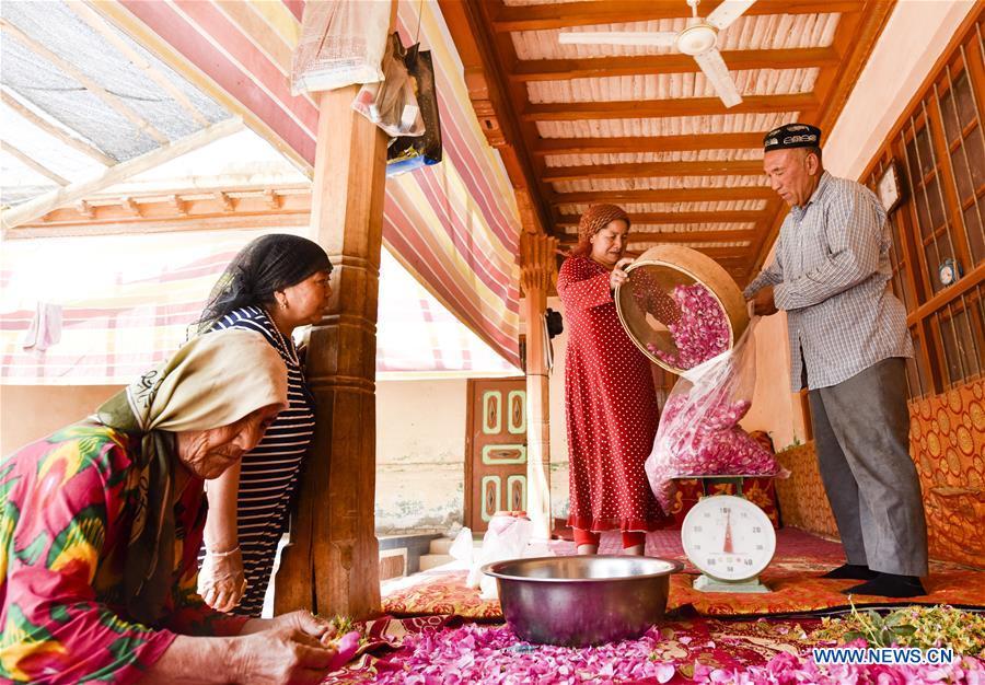 Flower grower Ruz and his wife Tajinisa weigh rose petals used for making rose sauce at a village in Hotan, northwest China\'s Xinjiang Uygur Autonomous Region, June 6, 2018. People in the village are good at making rose sauce, and that is an important source of income for them. (Xinhua/Zhao Ge)