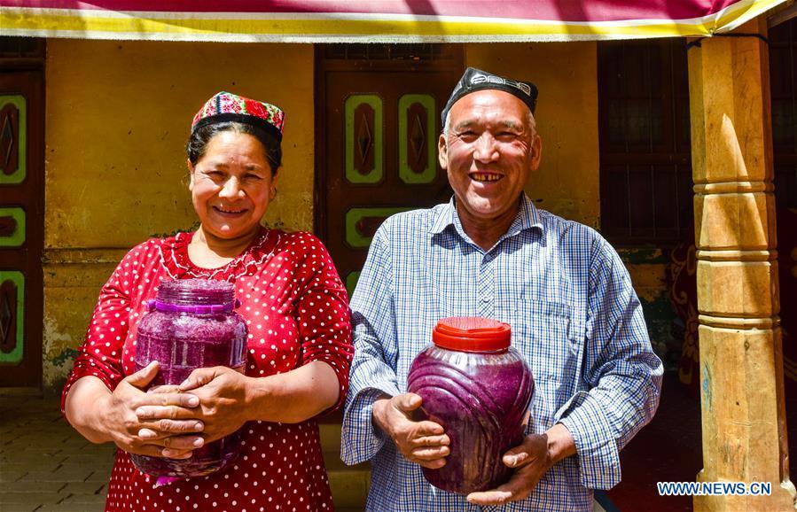 Flower grower Ruz and his wife Tajinisa show their handmade rose sauces at a village in Hotan, northwest China\'s Xinjiang Uygur Autonomous Region, June 6, 2018. People in the village are good at making rose sauce, and that is an important source of income for them. (Xinhua/Zhao Ge)