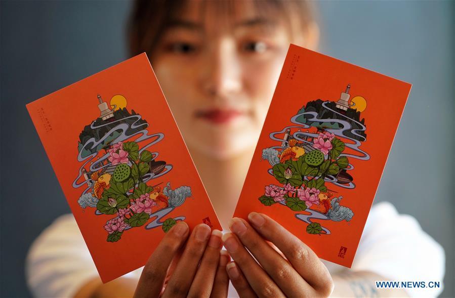 A staff member shows postcards with a creative design based on China\'s traditional 24 solar terms at a souvenir shop in Beihai Park, Beijing, capital of China, June 20, 2018. The 24 solar terms are a list of terms central to a calendar created in ancient China. Based on the movement of the sun, the calendar divides the year into 24 segments to guide farming over the four seasons. (Xinhua/Xing Guangli)