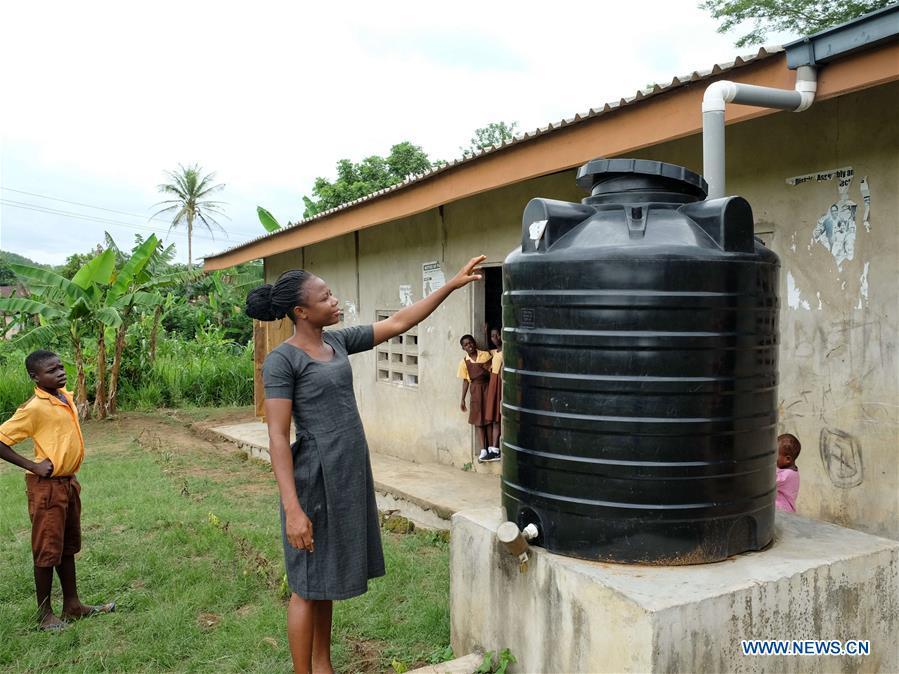 A primary school teacher shows a water tank which used to gather the rainwater from rooftops in Guayotse Village, Eastern Region, Ghana, on June 18, 2018. The government of China is providing 1,000 boreholes for hundreds of rural communities in six out of the ten regions of Ghana to bring clean water to the people. (Xinhua/Zhao Shuting)