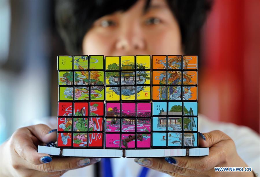 A staff member shows Rubik\'s Cubes with creative designs based on China\'s traditional 24 solar terms at a souvenir shop in Beihai Park, Beijing, capital of China, June 20, 2018. The 24 solar terms are a list of terms central to a calendar created in ancient China. Based on the movement of the sun, the calendar divides the year into 24 segments to guide farming over the four seasons. (Xinhua/Xing Guangli)