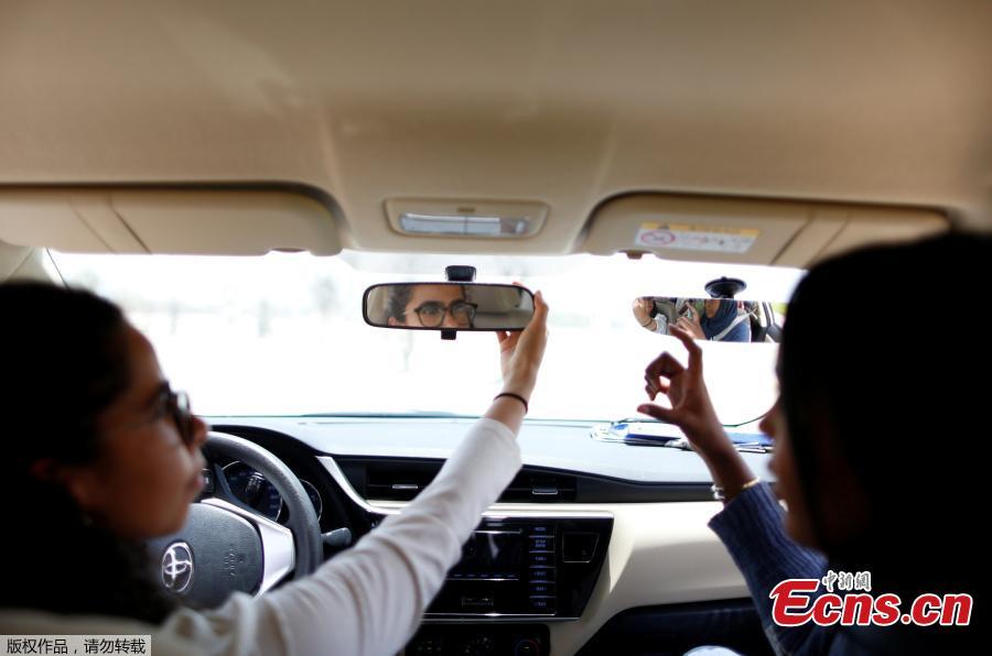 Trainee Maria al-Faraj (L) adjusts a mirror during a driving lesson with instructor Ahlam al-Somali at Saudi Aramco Driving Center in Dhahran, Saudi Arabia, June 6, 2018. (Photo/Agencies)