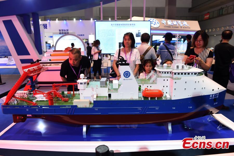 Visitors look at a model of the oceanic research vessel Tansuo-1, mother ship for manned submersible Shenhai Yongshi, at the 9th International Military and Civilian Dual-use Technology Exhibition in Chongqing, June 21, 2018. (Photo: China News Service/Zhou Yi)