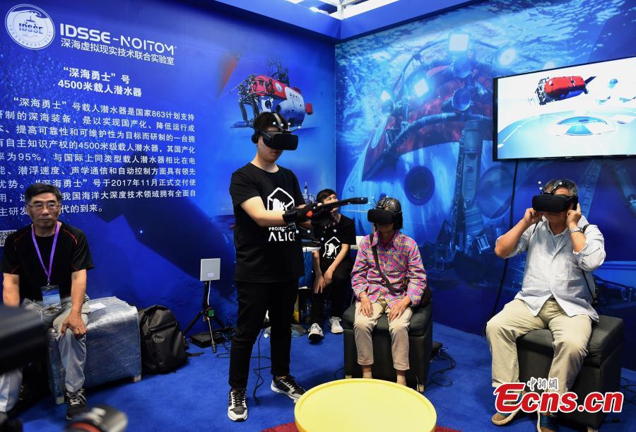 Visitors use VR to try out the manned submersible Shenhai Yongshi at the 9th International Military and Civilian Dual-use Technology Exhibition in Chongqing, June 21, 2018. (Photo: China News Service/Zhou Yi)
