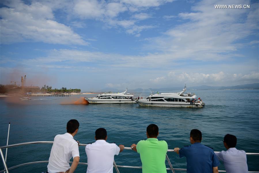 People look on as rescuers participate in an emergency drill on securing marine transportation in Sanya, south China\'s Hainan Province, June 22, 2018. (Xinhua/Sha Xiaofeng)