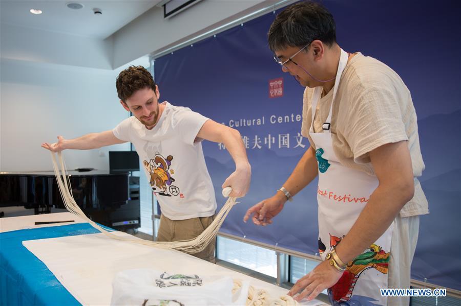 An Israeli man (L) learns noodle making skills during a Chinese food festival event at the Chinese Cultural Center in Tel Aviv, Israel, on June 22, 2018. (Xinhua/Guo Yu)