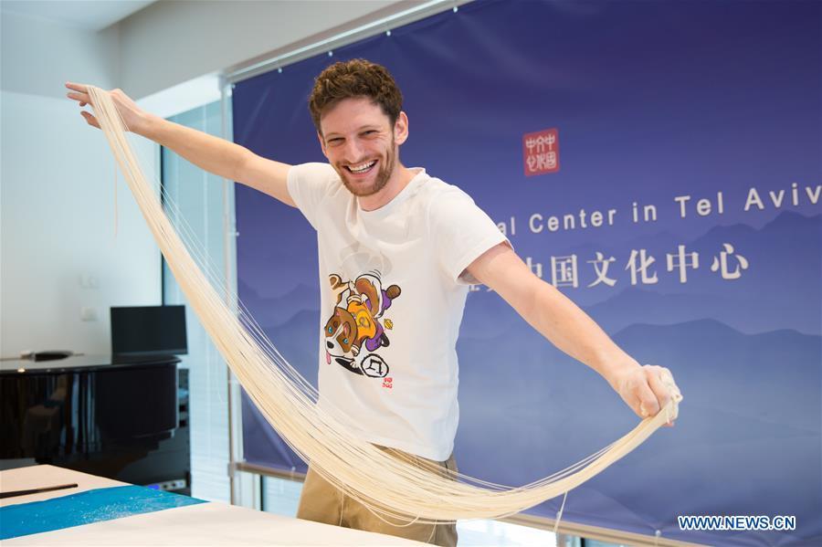 An Israeli man displays the noodle he made during a Chinese food festival event at the Chinese Cultural Center in Tel Aviv, Israel, on June 22, 2018. (Xinhua/Guo Yu)