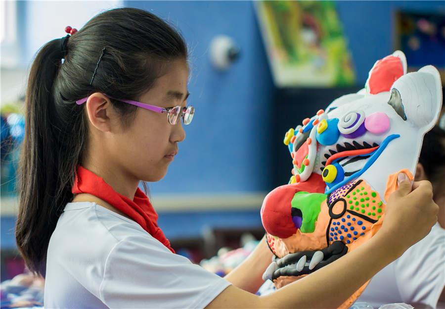 A student works on an auspicious beast mask at the Nanchafang Primary School in Hohhot, Inner Mongolia autonomous region, on June 27, 2018. (Photo/Asianewsphoto)