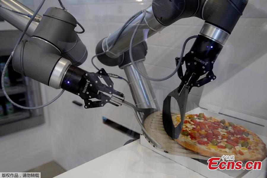 A pizzaiolo robot places a cooked pizza into its box before the customer’s eyes at the showroom of French food startup EKIM in Montevrain near Paris, France, June 26, 2018. Picture taken June 26, 2018. (Photo/Agencies)