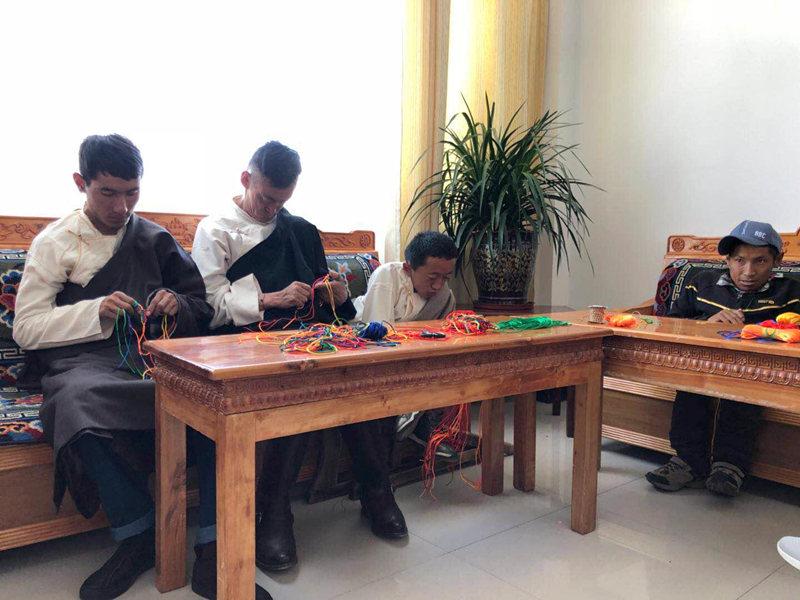 People with disabilities weave Tibetan knot at a welfare center in Lhasa, Tibet autonomous region, June 20, 2018. By making some handicrafts, these people can earn money to support their families. (Photo provided to chinadaily.com.cn)
Social security system
On the plateau with average elevation over 3,500 meters, a welfare center for the disabled provides dignified lives.
The center, which opened at Dagze county in 2015, can support 100 people with disabilities to live, undergo rehabilitative training, and enjoy entertainment avenues.
Currently, 18 people with disabilities are living in the center, and they are also taught some skills such as literacy, planting and hand knitting by teachers hired by the center.