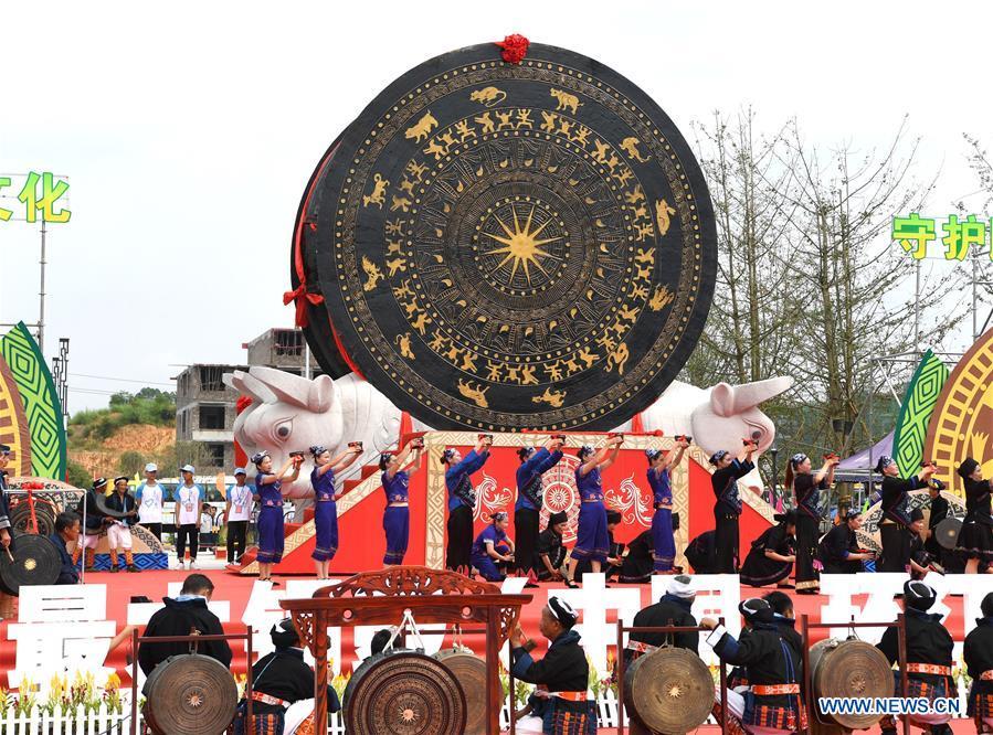People celebrate beside a gigantic bronze drum in Huanjiang Maonan Autonomous County, south China\'s Guangxi Zhuang Autonomous Region, June 29, 2018. The drum measures 6.68 meters in diameter and weighs 50 tons. It was recognized as the largest bronze drum by Guinness World Records. (Xinhua/Zhou Hua)