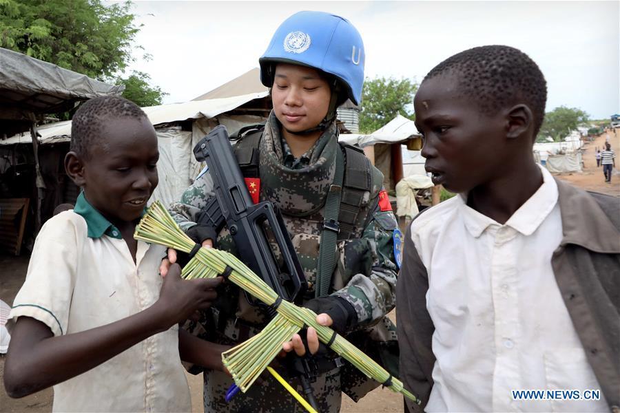 Local children present a tool rifle to Chinese peacekeeper Yu Peijie (C) as a gift at No.1 refugee camp of the United Nations, South Sudan, on April 30, 2018. Yu Peijie, 26-year-old, is the leader of the female peacekeeper unit of Chinese peacekeeping infantry batallion to South Sudan. She has a nickname called \