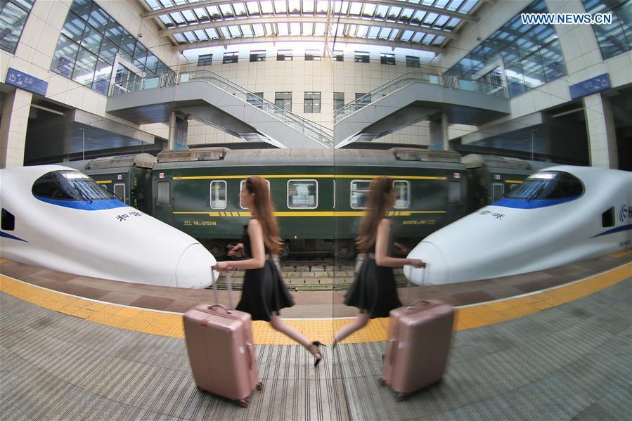 A passenger boards a bullet train at the Yantai Railway Station in Yantai, east China\'s Shandong Province, June 30, 2018. China\'s summer transport peak period will begin on July 1, with a total of 647 million passenger trips expected to be made by train. The period runs from July 1 to August 31, when students on summer vacation have time to travel or return home. (Xinhua/Tang Ke)