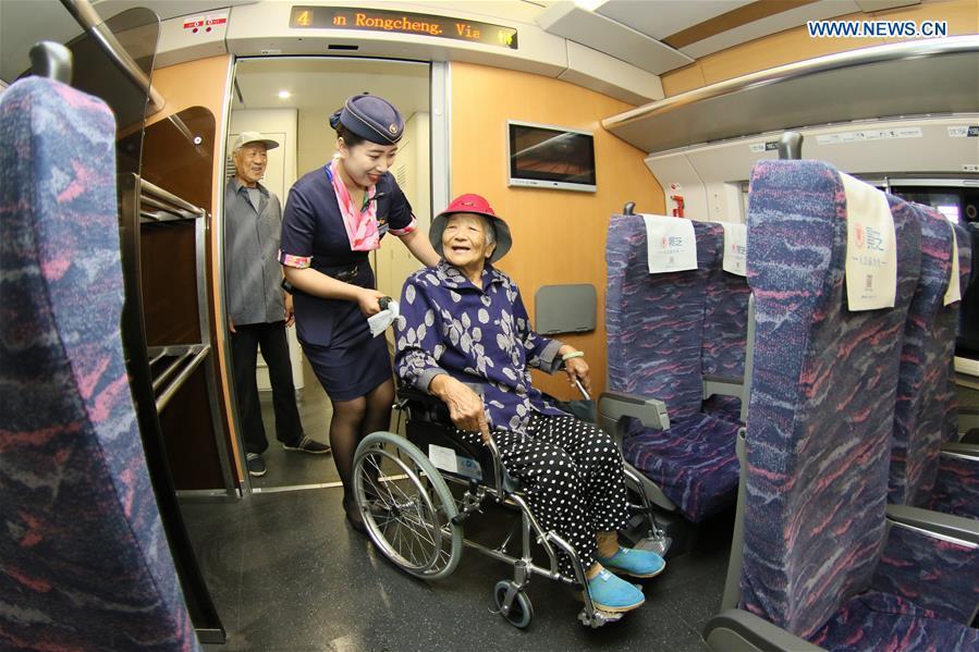 Conductor Zhang Xinxin (2nd R) helps a wheelchair user on the bullet train D6093 at the Yantai Railway Station in Yantai, east China\'s Shandong Province, June 30, 2018. China\'s summer transport peak period will begin on July 1, with a total of 647 million passenger trips expected to be made by train. The period runs from July 1 to August 31, when students on summer vacation have time to travel or return home. (Xinhua/Tang Ke)