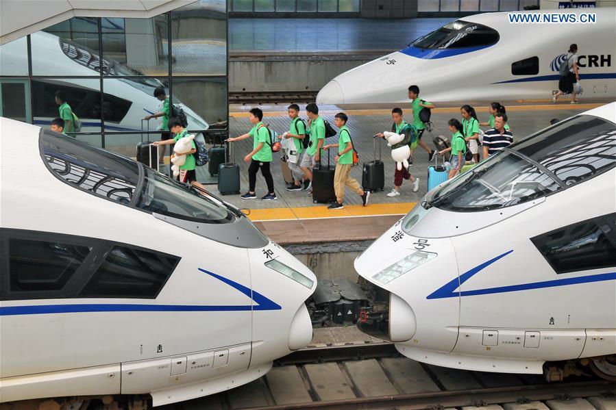 Children board a bullet train at the Yantai Railway Station in Yantai, east China\'s Shandong Province, June 30, 2018. China\'s summer transport peak period will begin on July 1, with a total of 647 million passenger trips expected to be made by train. The period runs from July 1 to August 31, when students on summer vacation have time to travel or return home. (Xinhua/Tang Ke)