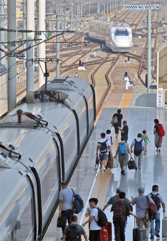 Passengers board a train at the Yantai Railway Station in Yantai, east China\'s Shandong Province, June 30, 2018. China\'s summer transport peak period will begin on July 1, with a total of 647 million passenger trips expected to be made by train. The period runs from July 1 to August 31, when students on summer vacation have time to travel or return home. (Xinhua/Tang Ke)