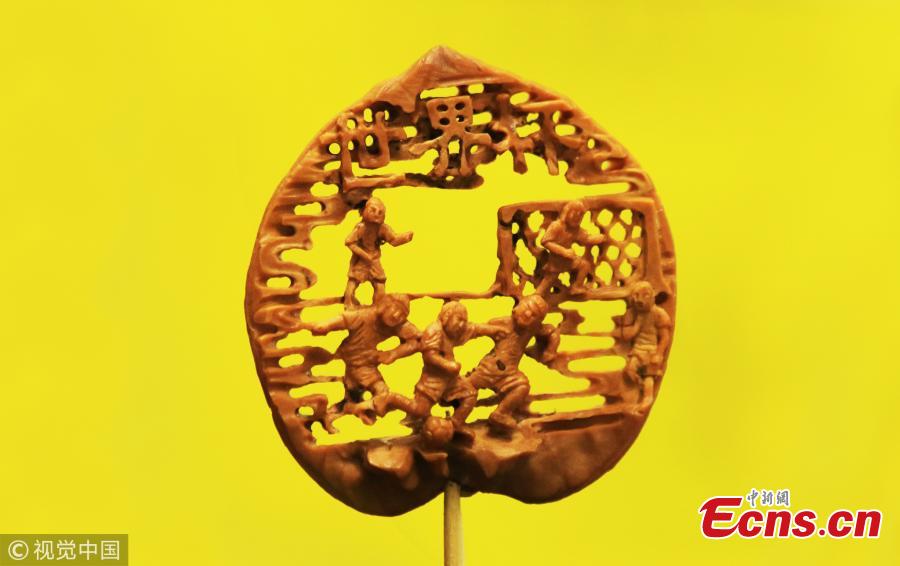 Folk artist Liu Jun, also a football fan, shows a peach pit creation in his home in Jining City, East China’s Shandong Province, July 1, 2018. Liu’s latest World Cup-inspired creation depicts six players competing on a coin-sized peach pit. Liu said he often stayed up late to watch the World Cup matches. (Photo/VCG)