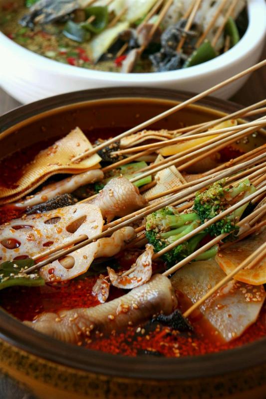 Boboji is cold skewers served in spicy broth. (Photo/Shine.cn)
Boboji
Though by name boboji is a chicken dish, it’s actually a spicy cold skewer snack featuring chicken, its offal and a variety of vegetables and meats. Originating in Leshan, boboji soaks a large amount of skewers in cold broth, often in large earthenware, hence the name bobo.
A true folk dish, boboji has a chicken broth-based stock, the oil in the dish comes from both the chicken and the chili oil. Ingredients like chicken heart, deboned chicken feet, black fungus, fried tofu and sausages are served together with the chicken in large bowls.
The unique aroma that separates boboji and other spicy snacks is the strong green peppercorn flavor from a green peppercorn infused oil seasoned with a lot of herbs and spices.
It has a very numbing yet refreshing feeling compared to the dried Sichuan peppercorns.