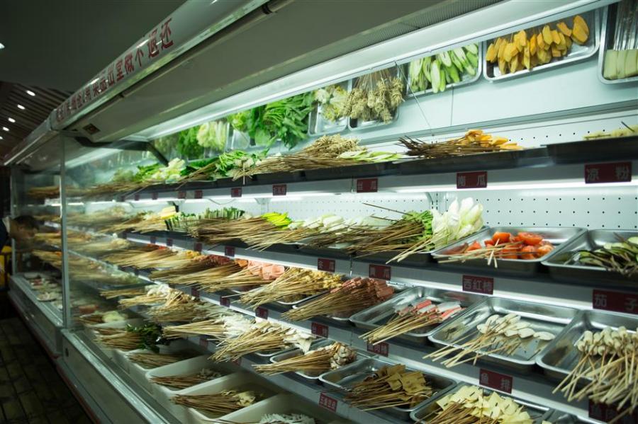 You can select all kinds of vegetables, meats and staple when ordring malatang. (Photo/Shine.cn)
Compared to hotpot that is best enjoyed with a group of people for wider selections of food, malatang is a perfect meal for one. To order malatang, simply pick up a small basket provided by the restaurant and take any ingredients displayed on the shelves and in the fridge. The ingredients are already washed and cut into smaller portions that allow diners to easily fit over a dozen varieties in one bowl.
Next, the cashier will count the number of ingredients in the basket to calculate the bill. Malatang is very cheap with vegetables costing 1 to 2 yuan (US$0.2-0.3) and protein 3 to 5 yuan. Once completed, the sticks or rubber bands that bounded the ingredients together are removed and the ingredients are cooked in a communal pot of broth.
It only takes minutes for the ingredients to be fully cooked and they are then served in a bowl with spicy soup.