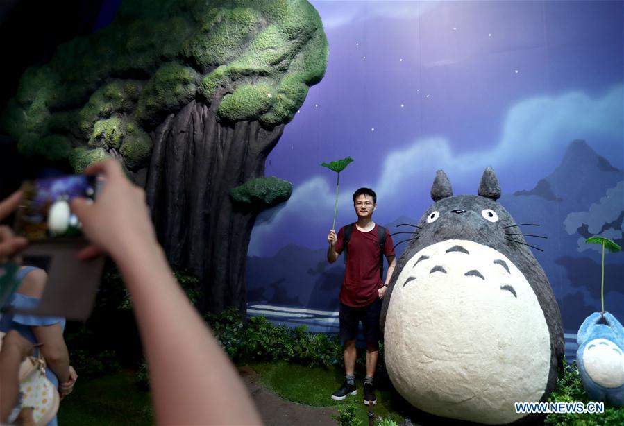 A man poses for a photo with Totoro, a cartoon figure in the Japanese animation fantasy film \