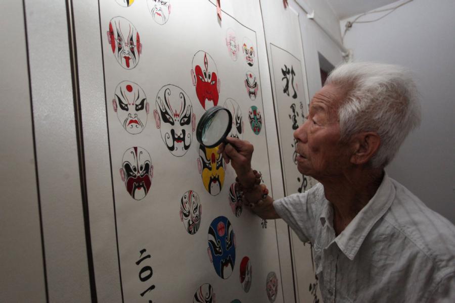 Zhang Fuli, 85, looks at his works of facial masks with a magnifying glass. (Photo//chinadaily.com.cn)