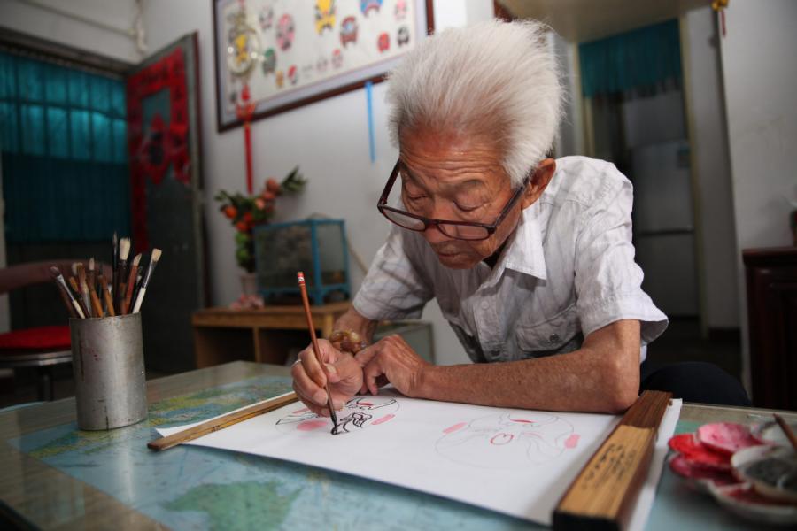 Zhang Fuli, 85, draws a facial mask of Peking Opera at home in Zhangjiakou, North China\'s Hebei Province.(Photo//chinadaily.com.cn)